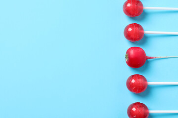 One radish among lollipops on light blue background, flat lay. Space for text