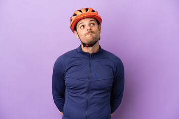 Young Brazilian cyclist man isolated on purple background and looking up - obrazy, fototapety, plakaty