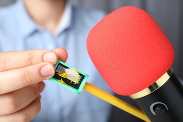 Woman making ASMR sounds with microphone, pencil and sharpener, closeup