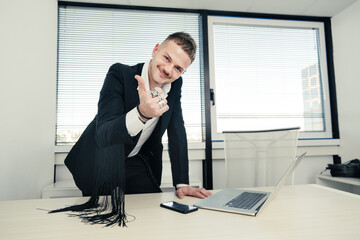 Uomo bianco con tatuaggi  vestito con una giacca con le frange fa il segno di ok con la mano nel...