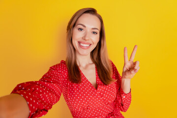 Beautiful lady girl show victory sign make selfie isolated on yellow background