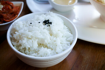 Rice in white cup on wood background and black sesame