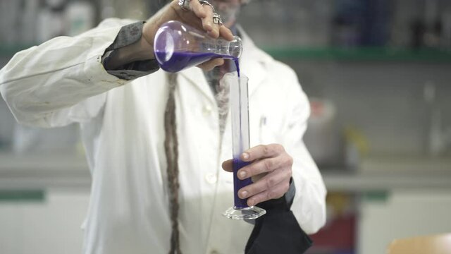Doctor Hand pouring smokey liquid into chemistry flask. Scientist experimenting in the laboratory