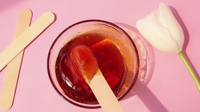 Sugar paste for shugaring on a pink background. Wooden spatulas for sugaring paste, tulip.