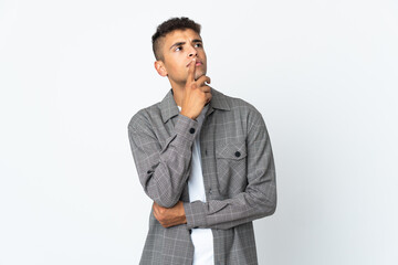 Young brazilian man isolated on white background having doubts while looking up