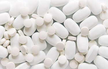 White pills on a white background. Oblong and round pills close-up. Healthcare and medicine.