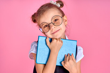 Cute little girl with glasses and books on pink background, spac