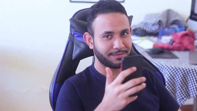 Man holding his phone and smilling at camera