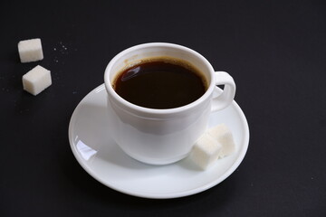 Black coffee and white sugar on a black background.