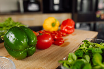 Foreground. Wooden cutting board, lies green pepper. Fresh ingredients for salad. healthy and...