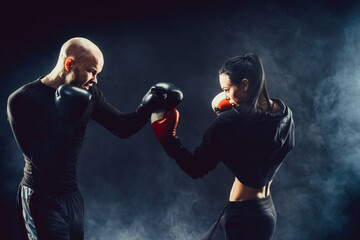 Woman exercising with trainer at boxing and self defense lesson