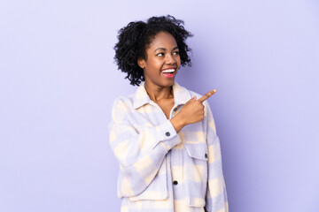 Young African American woman isolated on purple background surprised and pointing side