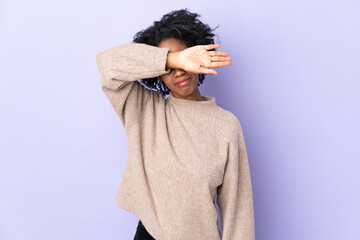Young African American woman isolated on purple background covering eyes by hands