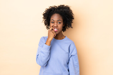 Fototapeta na wymiar Young African American woman isolated on beige background nervous and scared