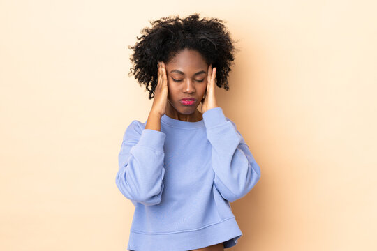 Young African American woman isolated on beige background with headache