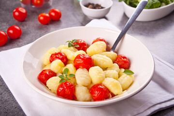 Homemade Italian gnocchi with tomato cherry on the wooden table