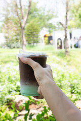 Naklejka na ściany i meble Female hand holding iced coffee drink in disposable take away cup