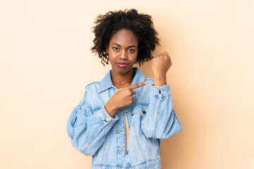 Young African American woman isolated on beige background making the gesture of being late