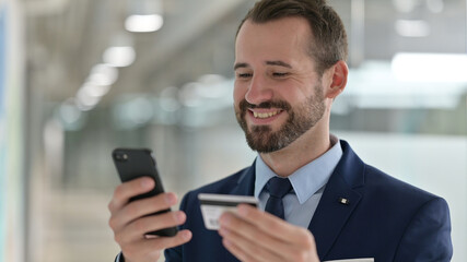 Portrait of Middle Aged Businessman making Successful Online Payment on Smartphone 