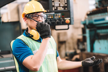 Work at factory.Asian worker man  working in safety work wear with yellow helmet and glasses l ear muff using walkie talkie .male technician asia in factory workshop industry machine professional