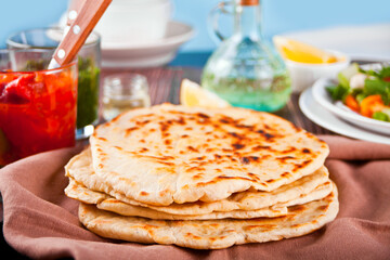 Homemade Indian naan flatbread with fresh salad and dips on the dinner table.