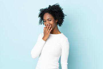 Fototapeta na wymiar Young African American woman isolated on blue background happy and smiling covering mouth with hand