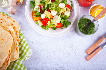salad of fresh cherry tomatoes, mozzarella, basil and other greens on the dinner table with pita flat bread