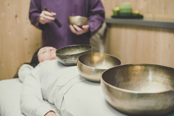 Soft focus view of a woman practicing holistic activities with Tibetan bells. Meditation and mindfulness exercises for calm and clear your mind. Wellness, health, relax, and inner well-being concept.