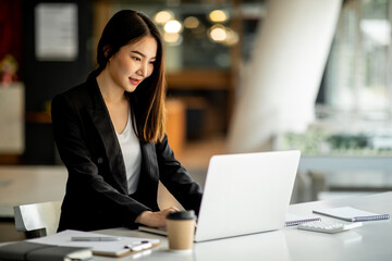 Portrait of Accounting businesswoman working on note laptop computer and analyzing real estate investment data, Financial and tax systems concept.
