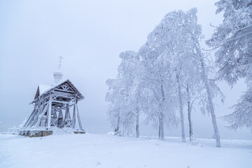 an iron bell covered with frost and snow on a frosty day on the top of Mount Belorie next to the Belogorsk monastery. Ural, Russia.