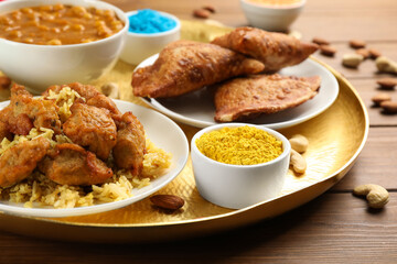Traditional Indian food and color powder on wooden table, closeup. Holi festival celebration