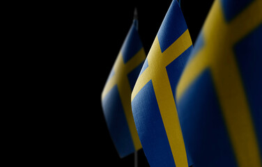 Small national flags of the Sweden on a black background
