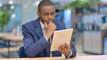 Serious African Businessman Reading on Tablet in Office 