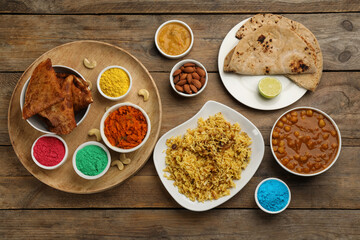 Traditional Indian food and color powders on wooden table, flat lay. Holi festival celebration