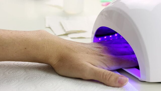 Manicure with led lamp in process. Hand in drying machine
