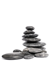 Black pebbles or zen stones stacked on top of each other like a pyramid, isolated on white background. Harmony, balance and meditation, spa, massage, relax concept.
