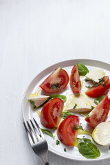 Homemade Italian caprese salad with sliced tomatoes, mozzarella cheese, basil and olive oil