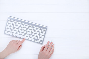 Female hands typing on computer keyboard and holding mouse on white background