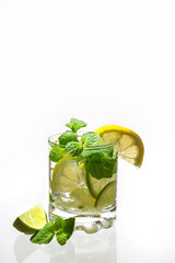 Citrus water with ice in a glass decorated with lemon, lime and mint slices and on a white background. Fresh summer drink. Detox. Healthy food rich in vitamins and antioxidants. Copy space