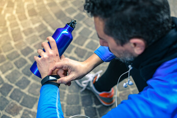 Close up of male hands using fitness app on smart watch. Man resting after jogging reading run results. Running man with smartwatch recording data about sport activity Boy checking wearable technology