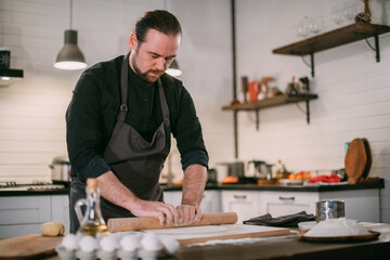 A male chef prepares noodles at home in the kitchen.