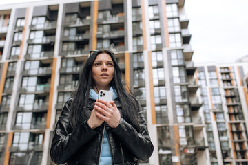 Young woman using mobile phone. Beautiful brunette woman using smartphone and looking away, thinking about something . Technology concept