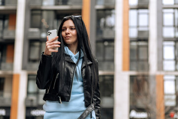 Young beautiful brunette girl on the street makes a selfie on the phone