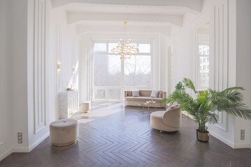 Fototapeta na wymiar very light and bright interior of luxurious cozy living room with chic soft beige furniture with gold metallic elements, huge window to the floor and wooden parquet
