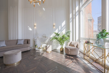 very light and bright interior of luxurious cozy living room with chic soft beige furniture with gold metallic elements, huge window to the floor and wooden parquet
