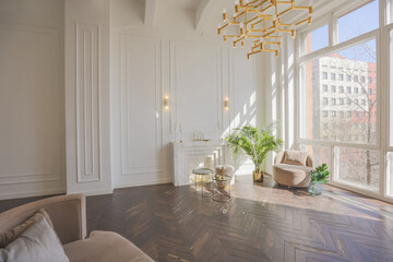 very light and bright interior of luxurious cozy living room with chic soft beige furniture with gold metallic elements, huge window to the floor and wooden parquet