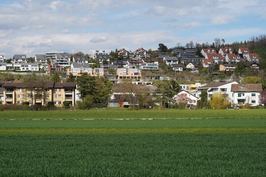 Village Birmensdorf in canton Zurich Switzerland, a cutout of a residential quarter on a slight slope. In the foreground there is agricultural field.