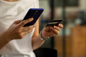 Close up woman hand using credit card and smartphone laptop for buying online shopping