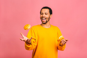 Diet concept. Hungry african american bearded man eating donuts isolated on pink background.