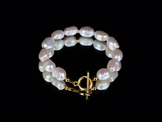 Luxury elegant baroque pearl golden bracelet on black mirror background
